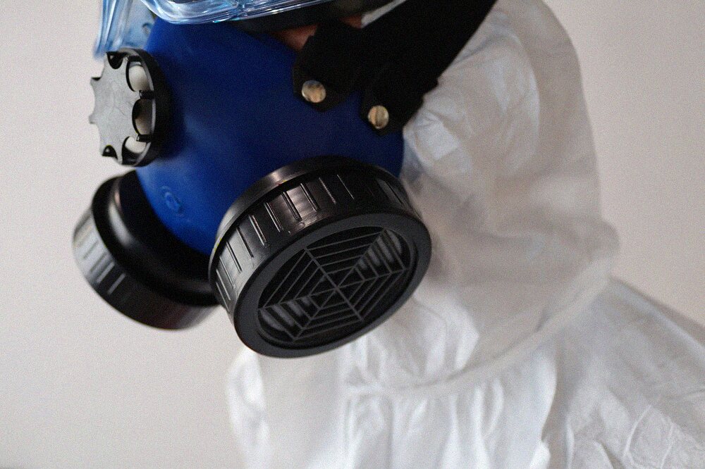 A full-face respirator worn with a disposable protective coverall